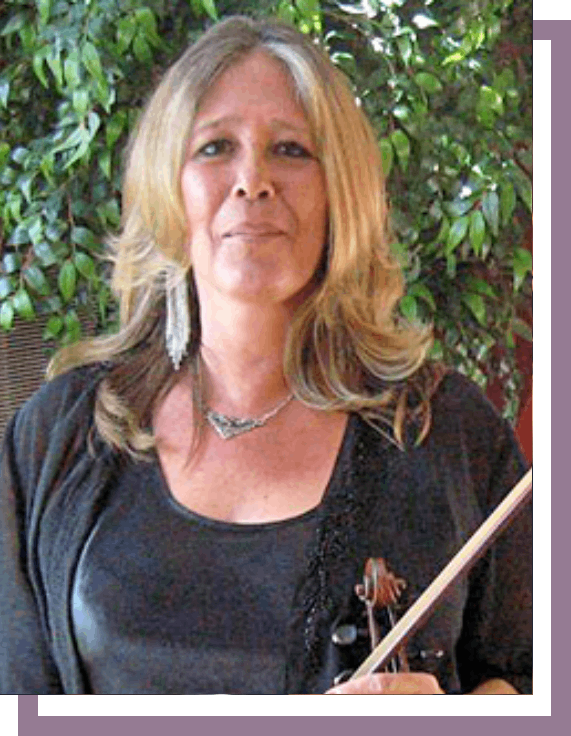 A woman holding a violin in front of a tree.